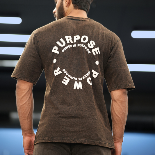 A person wearing a brown oversized distressed t-shirt with the text 'PURPOSE IS POWER' on the back.